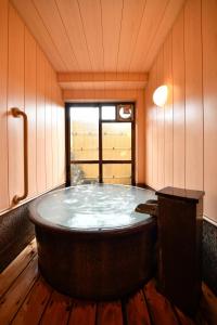 a large bath tub in a room with a window at Ryokan Tamura in Kusatsu