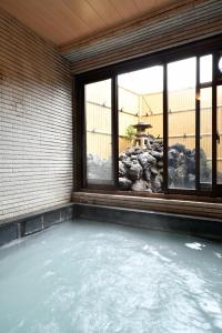 a hot tub in a room with a window at Ryokan Tamura in Kusatsu