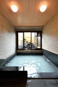 a room with a pool of water with two lights at Ryokan Tamura in Kusatsu