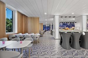 a dining room with tables and white chairs at prizeotel Hamburg-St.Pauli in Hamburg