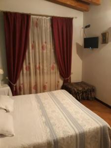 um quarto com uma cama e uma janela com cortinas vermelhas em La Tenuta dell 'Orta em Bolognano