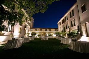 a courtyard of a building at night with white tables at Hotel Parco delle Fontane in Syracuse