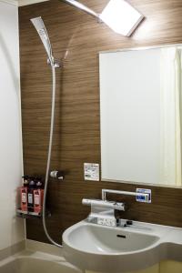 La salle de bains est pourvue d'un lavabo blanc et d'un miroir. dans l'établissement Fukuoka Floral Inn Nishinakasu, à Fukuoka