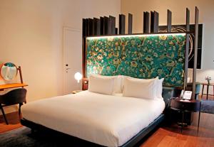 a bedroom with a large bed with a painting on the wall at Hotel Mercer Sevilla 5 GL in Seville