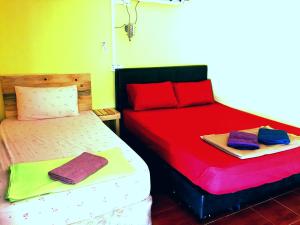 two beds in a room with red and green at Rainbow Tioman Cottage in Kampong Juara
