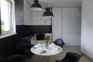 kuchnia z białym stołem i czarnymi krzesłami w obiekcie Impresja 42 Apartament z garażem w Kołobrzegu