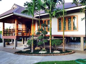 a house with palm trees in front of it at Magmai Riverside in Tak