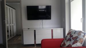ポゴジェリツァにあるApartament w przy plażyのリビングルーム(テレビ、赤いソファ付)