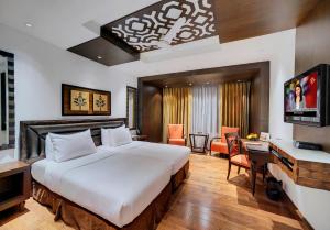 ein Hotelzimmer mit einem großen Bett und einem TV in der Unterkunft Mayfair Convention in Bhubaneshwar