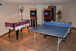 due tavoli da ping pong in una stanza con videogiochi di Parkhotel Fedora a Campitello di Fassa