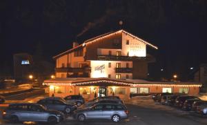 a large building with cars parked in a parking lot at Parkhotel Fedora in Campitello di Fassa