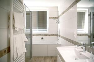 ein weißes Badezimmer mit einer Badewanne und einem Waschbecken in der Unterkunft Hotel - Restaurant Valley Rose in Wien