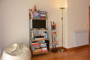 um quarto com televisão e uma prateleira com livros em Casa da Praia Matosinhos by Flat in Porto em Matosinhos