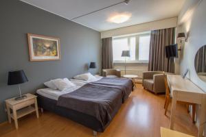 ein Hotelzimmer mit einem großen Bett und einem Schreibtisch in der Unterkunft Economy Hotel Savonia in Kuopio