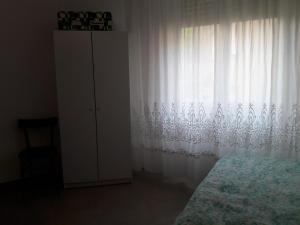 a bedroom with a white curtain and a dresser and a window at casa maria in Sestri Levante