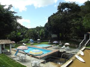 a swimming pool with umbrellas and tables and chairs at Estancia Vale das Flores in Pacoti
