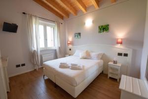una camera bianca con un letto bianco e una finestra di Le Bignele a Marano di Valpolicella