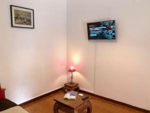 a living room with a table and a tv on the wall at Holidays Madeira in São Vicente