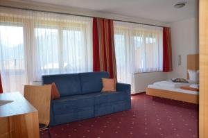 a living room with a blue couch and a bed at Gasthof Hirschen in Sibratsgfäll