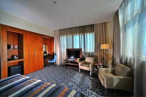 a hotel room with a bed and a living room at Ramada Abu Dhabi Corniche in Abu Dhabi
