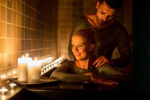 Ein Mann steht neben einer Frau in einem Badezimmer mit Kerzen. in der Unterkunft Terme Tuhelj Hotel Well in Tuheljske Toplice