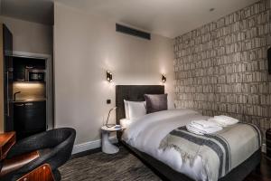 a hotel room with a bed and a chair at The Knaresborough by Nestor in London