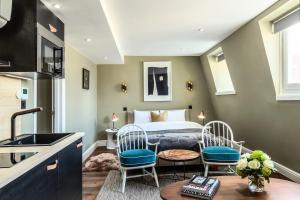a bedroom with a bed and two chairs and a sink at The Knaresborough by Nestor in London
