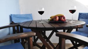 a wooden table with two glasses of wine and fruit at Asterias Hotel in Porto Koufo