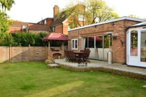 a backyard with a patio with a table and a grill at Lyndricks House in Ascot