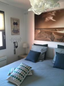 uma cama com almofadas azuis e uma fotografia na parede em detente rochelaise em Aytré