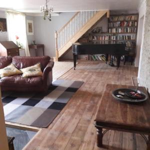 a living room with a couch and a piano at Gernos Farmhouse in Llandysul