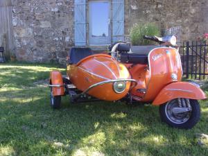 an orange vespa with a side car parked in the grass at cool la source in Burdignes