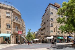 eine Gruppe von Menschen, die eine Straße mit Gebäuden entlang gehen in der Unterkunft DEM Hotel in Jerusalem