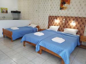 リオにあるHotel Apollonの青いシーツとタオルが備わる客室内のベッド2台