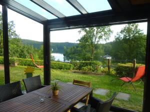 a screened porch with a table and chairs and a view of a lake at Panoramaferienhaus Sorpesee in Sundern