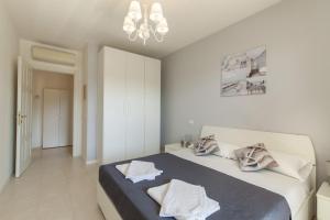 - une chambre blanche avec un lit et une couverture bleue dans l'établissement Le Domus lovely apartment, à Quartu SantʼElena