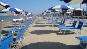 a row of blue chairs and umbrellas on a beach at Hotel Boutique Il Castellino Relais in Vieste