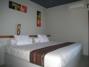 1 dormitorio con 1 cama blanca con sábanas y almohadas blancas en Cafe Alberto B and B en Senggigi 