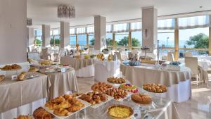 - un buffet avec des tables remplies de pain et de viennoiseries dans l'établissement Hotel Abner's, à Riccione