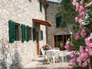 een patio met een tafel en stoelen en roze bloemen bij Belvilla by OYO La Casa dei Cinque Olivi in Quarrata