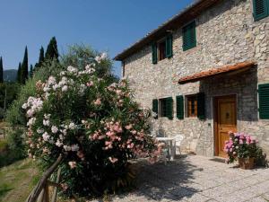 una casa de piedra con un arbusto de flores delante de ella en Belvilla by OYO La Casa dei Cinque Olivi en Quarrata