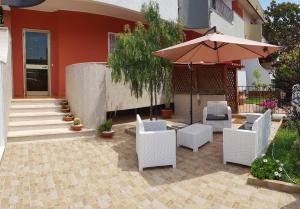 eine Terrasse mit weißen Stühlen und einem Sonnenschirm in der Unterkunft Cooking and Dreaming in Bari