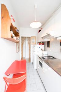 una cocina blanca con una silla roja. en Veeve - Contemporary in Balard en París