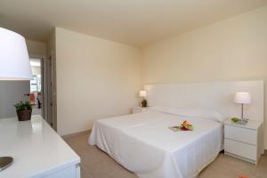a white bedroom with a bed with a plate of flowers on it at Apartamentos Nucleo Cristal in Torremolinos
