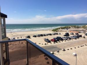 uma vista para uma praia com carros estacionados na areia em La Timonerie - La Caraque 35, vue mer et dunes classé 2 étoiles em Fort-Mahon-Plage