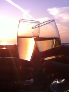 La Timonerie - La Caraque 35, vue mer et dunes classé 2 étoiles في فورت ماهون بلاج: كأسين من النبيذ أمام غروب الشمس