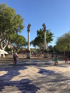 a group of people walking around a park with two pillars at CLB Apartamento Alameda in Seville