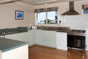 cocina con armarios blancos y ventana grande en Seagulls Guesthouse, en Mount Maunganui