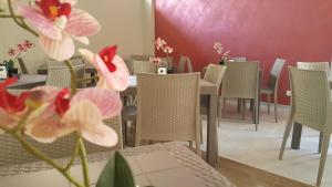 ein Esszimmer mit Tischen, Stühlen und rosa Blumen in der Unterkunft A'MANTIA HOTEL in Amantea