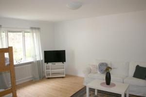 uma sala de estar com um sofá branco e uma televisão em Borggården Apartment em Hultsfred
